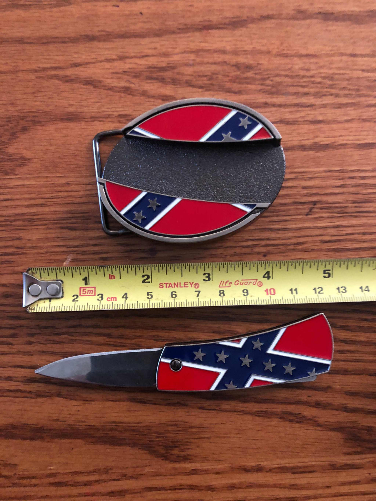 Oval metal belt buckle featuring Confederate rebel flag design with concealed stainless steel knife blade